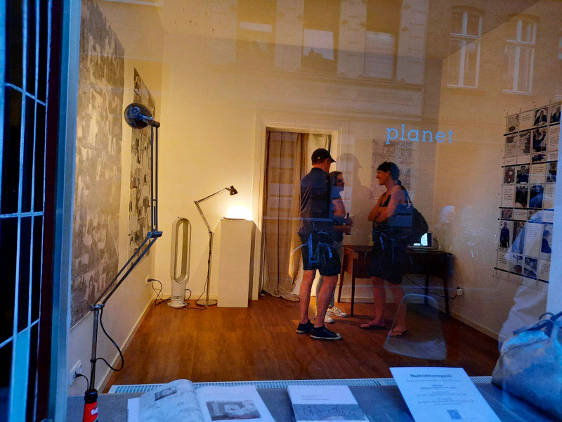 Blick durch das Schaufenster einer Galerie auf die Ausstellungsbesucher einer Vernissage